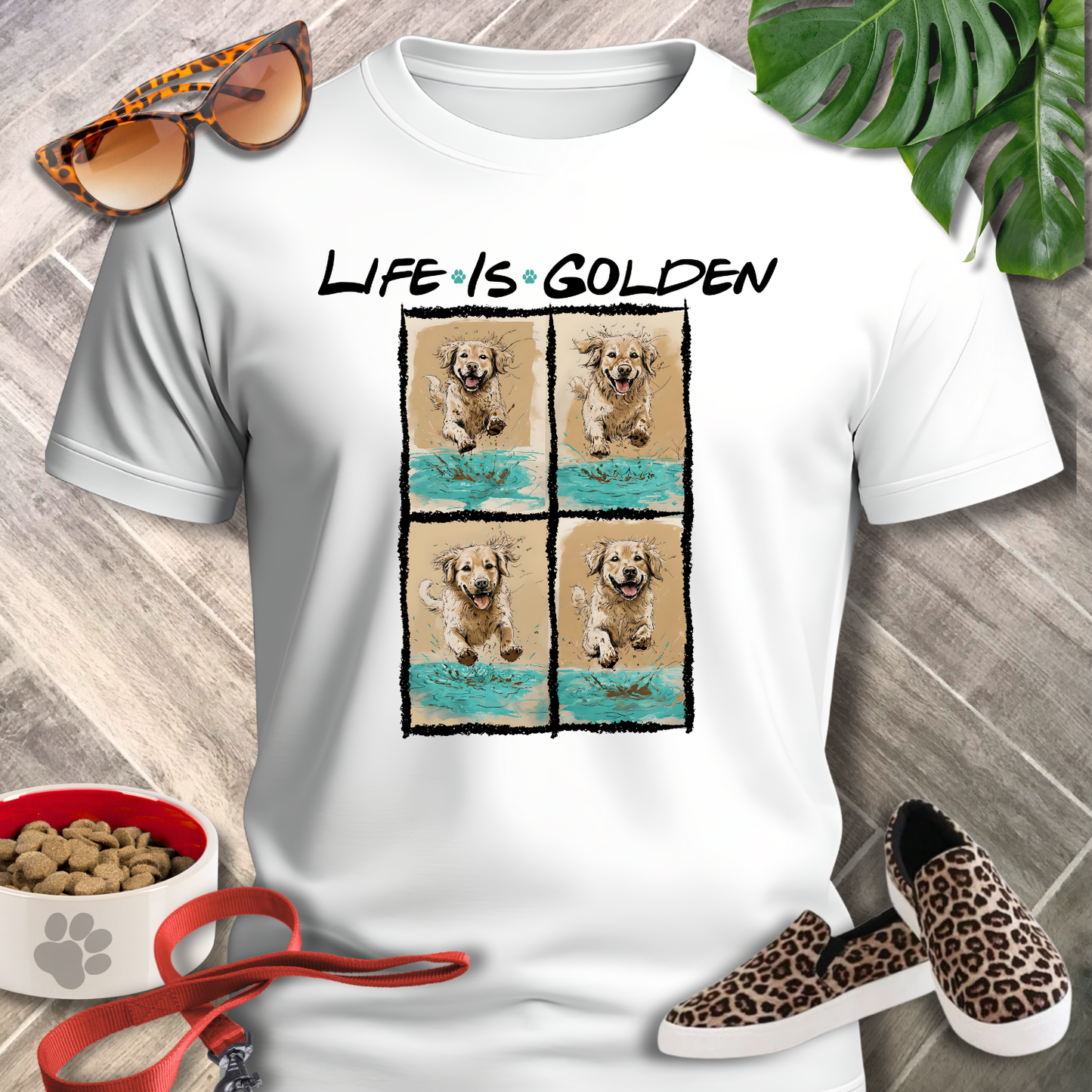 White t-shirt with 'Life is Golden' design featuring a dog, surrounded by sunglasses, shoes, and pet accessories on a wooden surface.