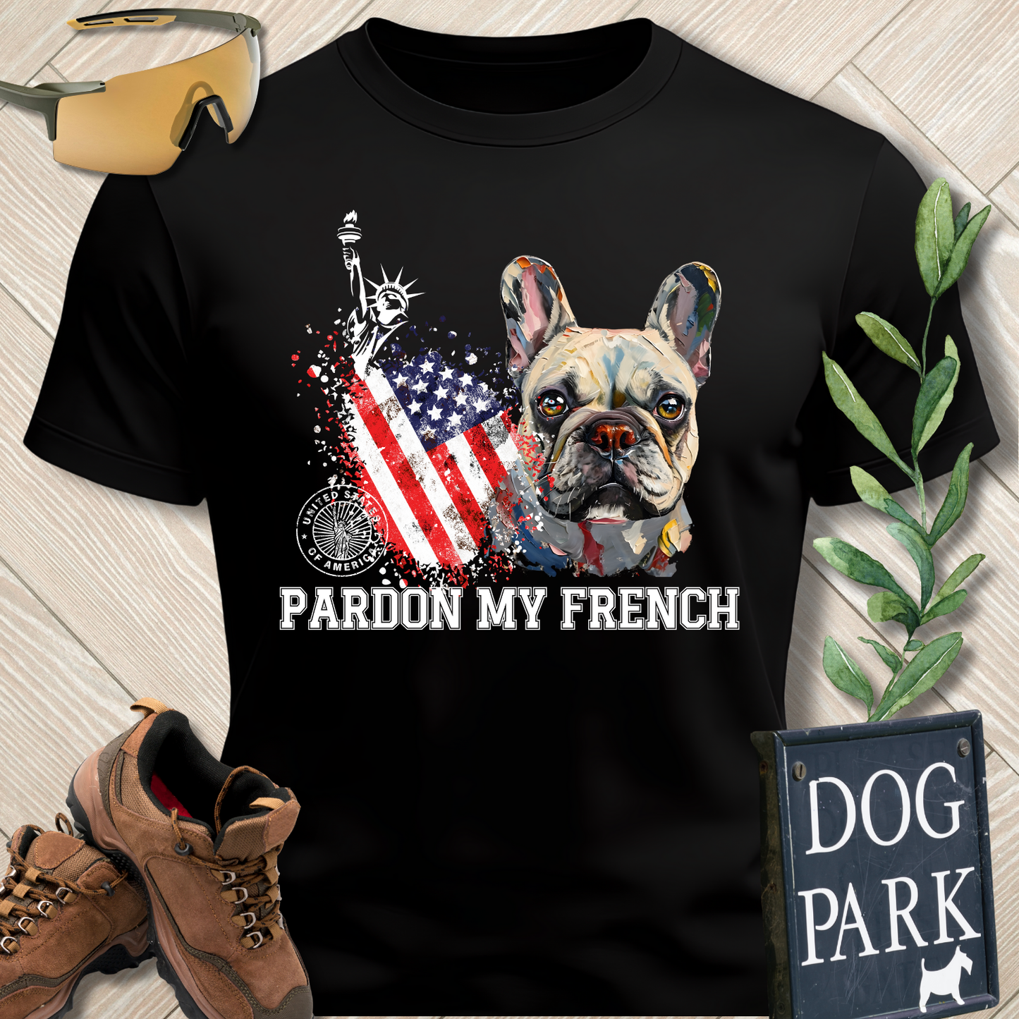 Black t-shirt with a dog graphic and 'Pardon My French' text on a wooden surface with accessories.