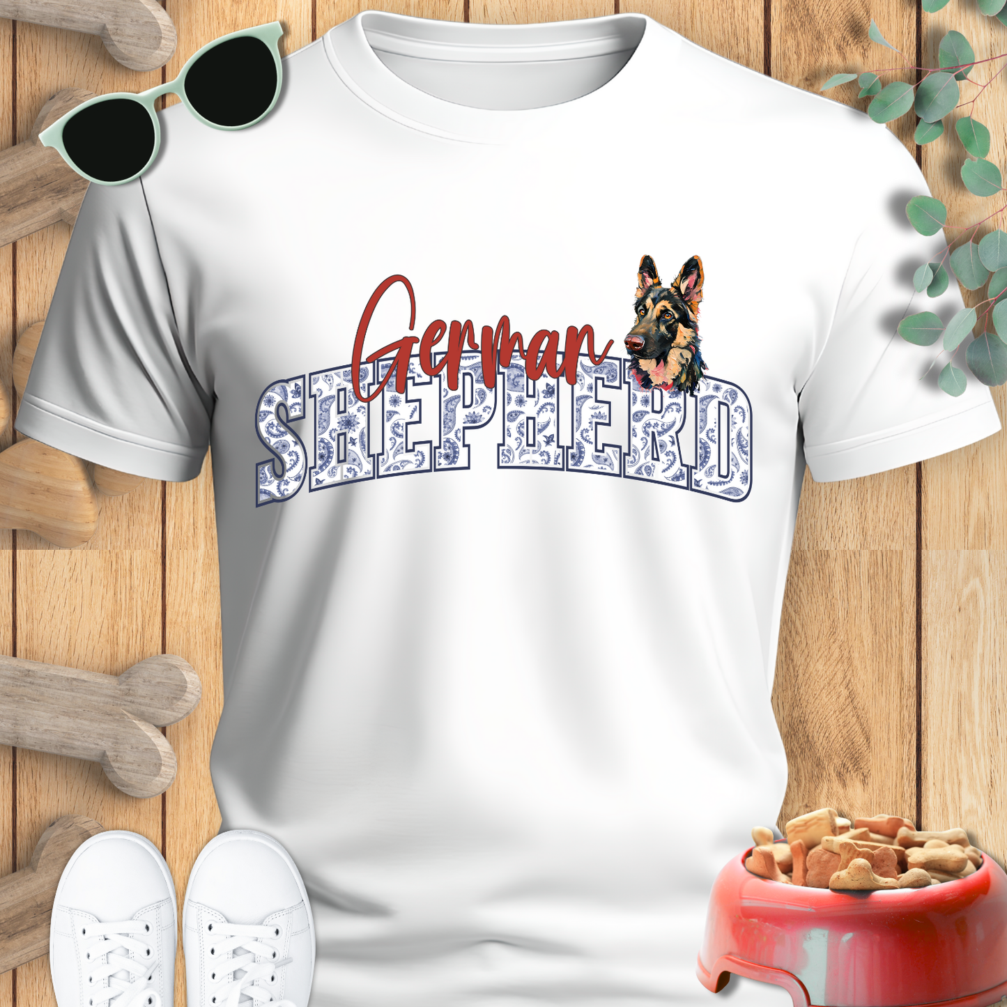 White t-shirt with 'German Shepherd' design on a wooden surface with pet accessories.