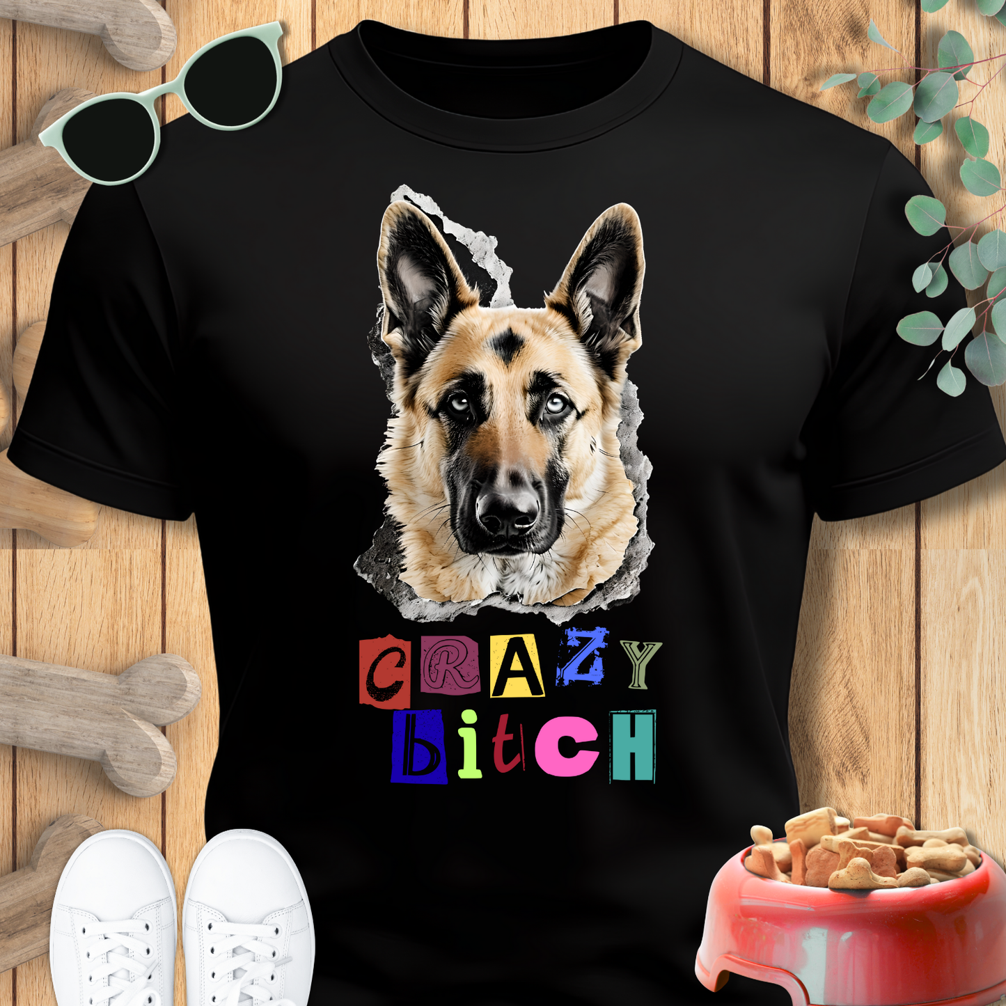 Black t-shirt with a German Shepherd graphic and colorful text on a wooden surface with pet accessories.