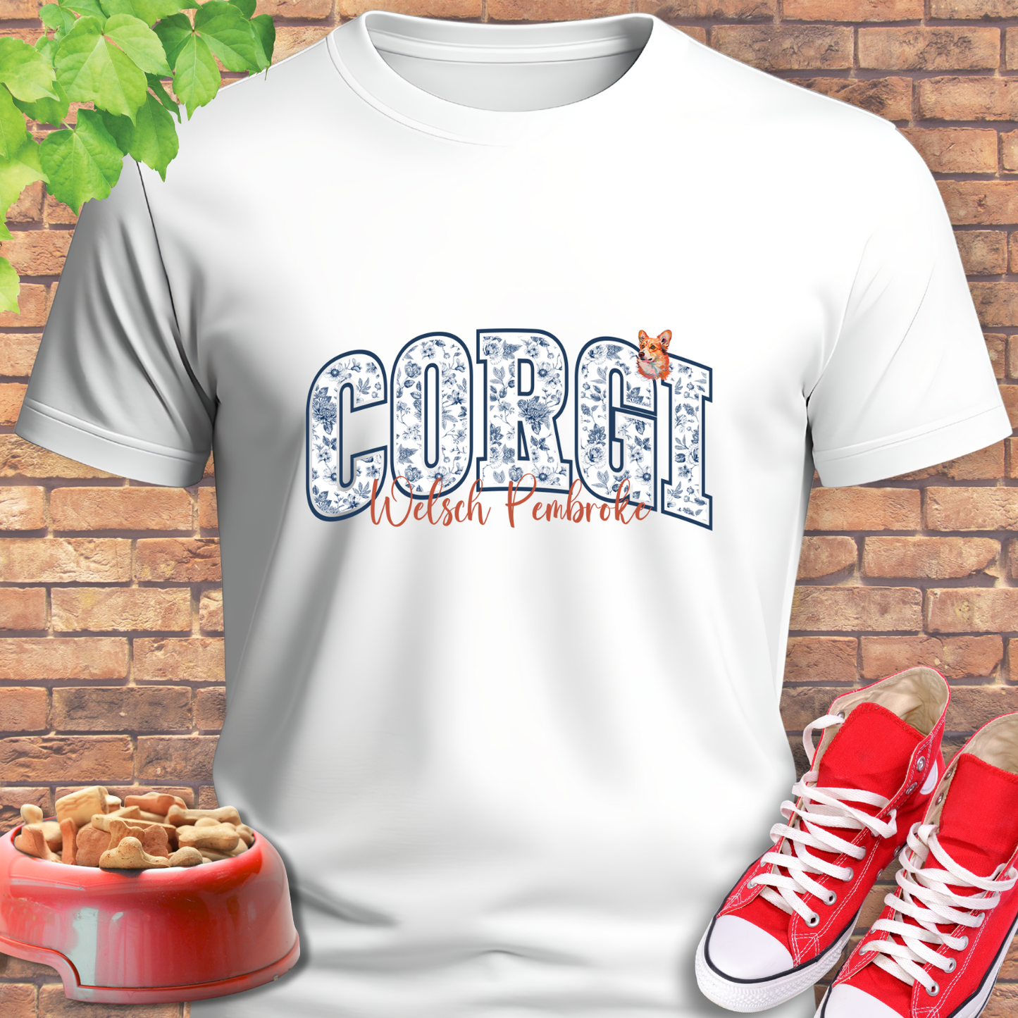 White t-shirt with 'Corgi Welsh Pembroke' design, red sneakers, and dog bowl on a brick background