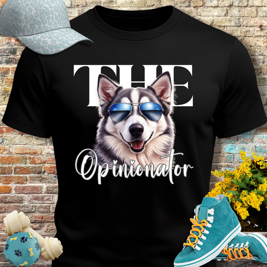 Black t-shirt with a husky graphic and text, placed against a brick wall with shoes and a cap on either side.