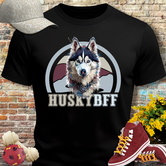 Black t-shirt with husky graphic and 'HUSKYBFF' text, placed against a brick wall with shoes and a cap on either side.
