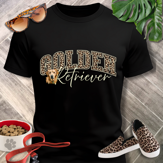 Black t-shirt with 'Golden Retriever' design, surrounded by sunglasses, shoes, and a bowl on a wooden surface.