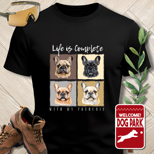 Black t-shirt with dog-themed design on a wooden floor with shoes and a plant.