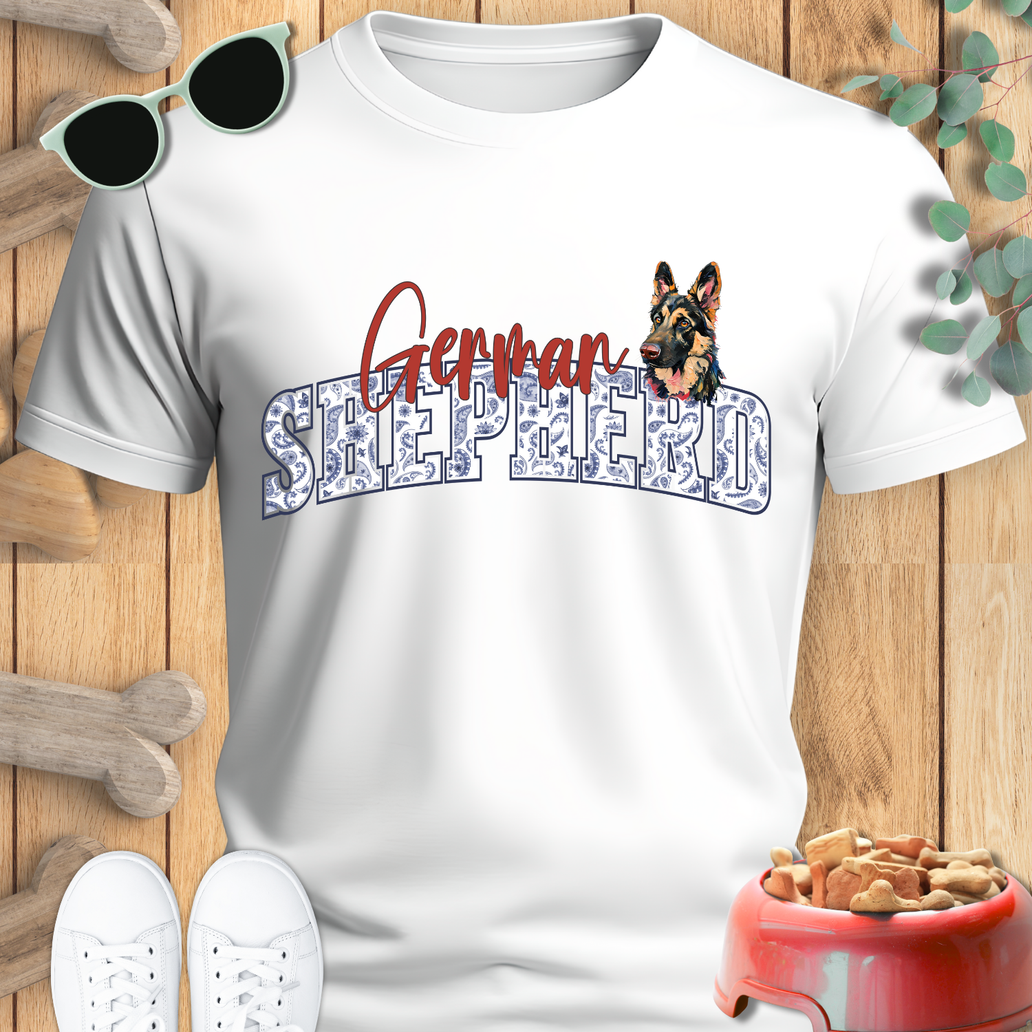White t-shirt with 'German Shepherd' design on a wooden surface with pet accessories.
