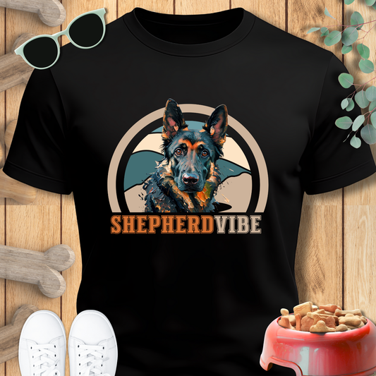 Black t-shirt with a dog graphic and 'Shepherd Vibe' text on a wooden surface with pet accessories.