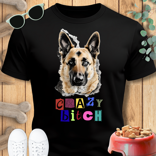Black t-shirt with a German Shepherd graphic and colorful text on a wooden surface with pet accessories.