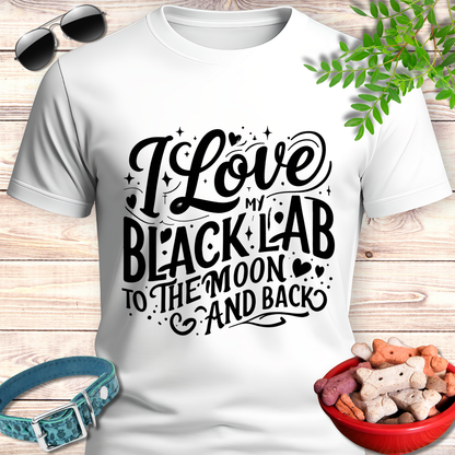 White t-shirt with 'I Love My Black Lab To The Moon And Back' text, sunglasses, dog collar, and treats on a wooden surface.