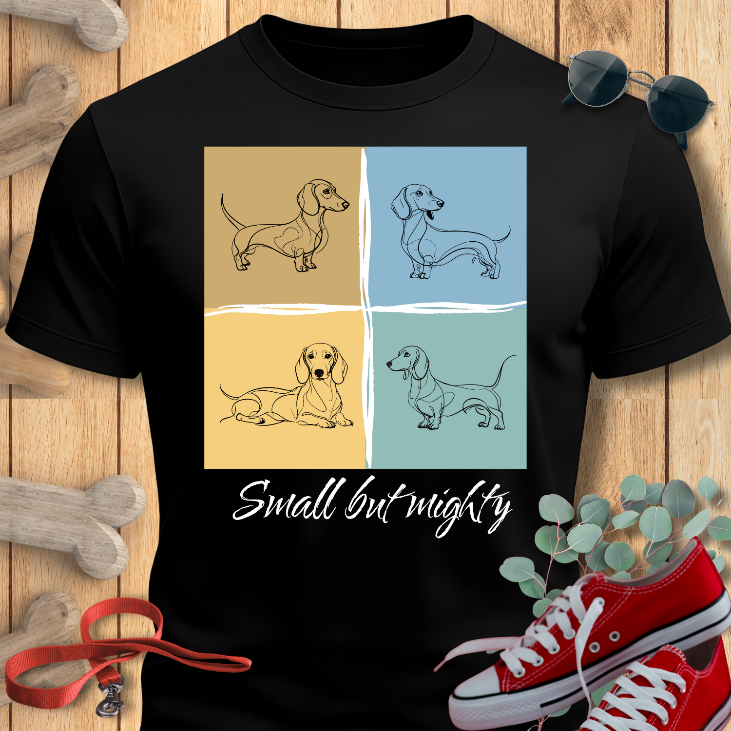 Dachshund shirt Small But Mighty in Black with dachshund illustrations and 'Small but mighty' text on a wooden surface with accessories.