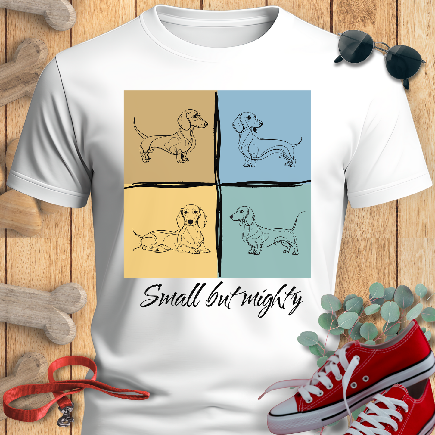 Dachshund shirt Small But Mighty in White with dachshund design and 'Small but mighty' text on a wooden surface with shoes and plant.