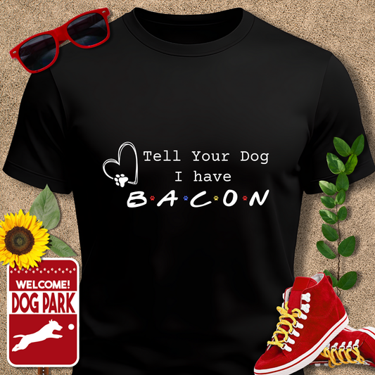Black t-shirt with 'Tell Your Dog I have Bacon' text, sunglasses, red sneakers, sunflower, and 'Welcome to the Dog Park' sign on a beige background.